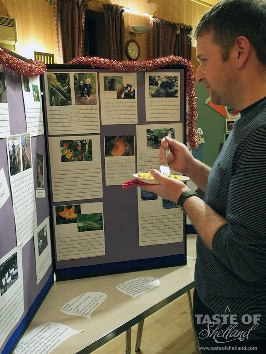 A parent enjoys some of the food the children made while browsing the displays