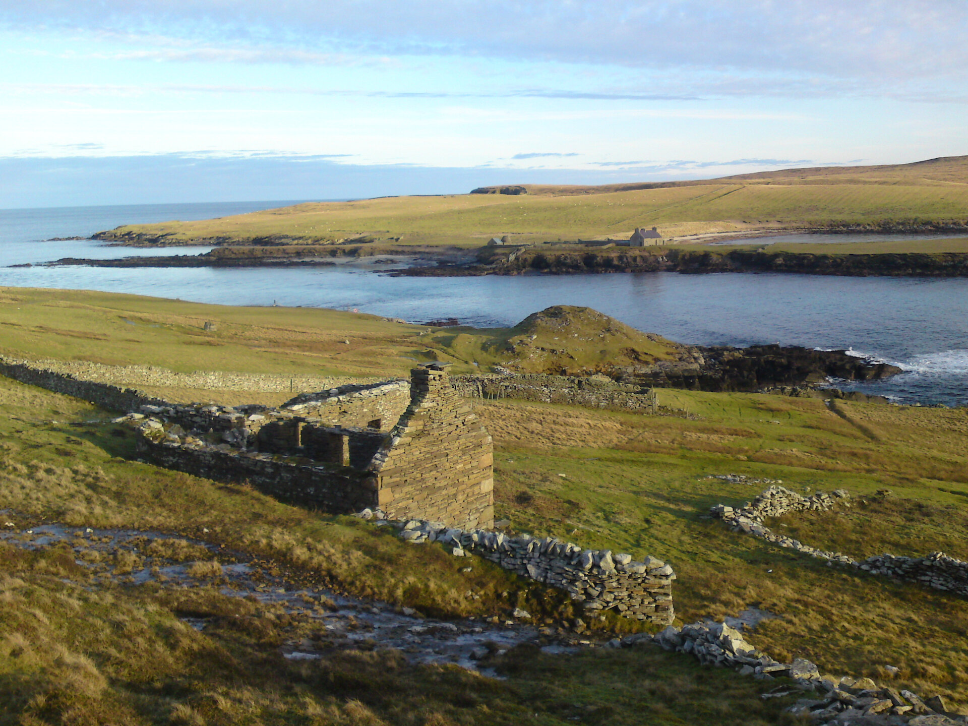 A stone-built coastal Iron Age broch alongside more recent drystone structures and enclosures at Noss Sound, Bressay.