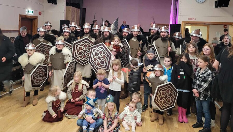 The Bressay Up Helly Aa Jarl's Squad from 2023 meets young islanders in the community hall.