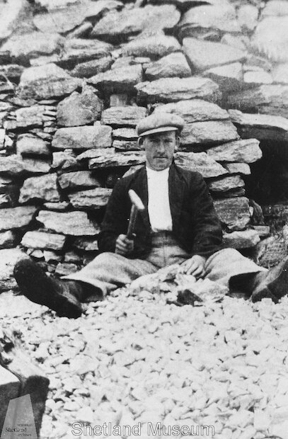 William Manson of Brinna breaking up burnt limestone at Fladdabister in 1932 with the lime kiln behind him