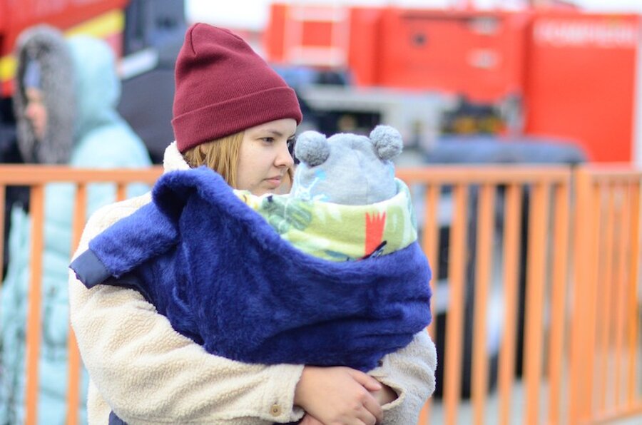 A woman refugee carries a baby off the ferry ramp at Isaccea, Romania | Jen Stout